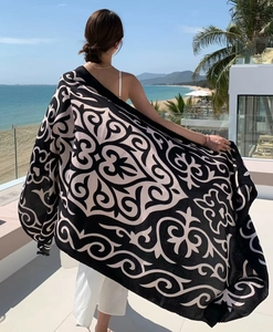Close-up of decorative paisley patterns on a black beach shawl during a sunny resort vacation