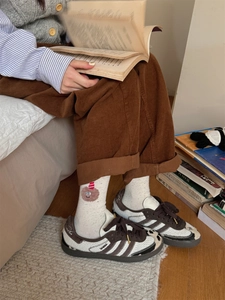 Close-up of cute bear embroidery on white cotton mid-calf socks worn with corduroy pants