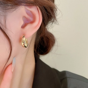 Gros plan d'un modèle portant des boucles d'oreilles créoles dorées en forme de goutte