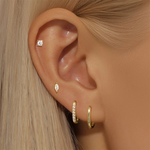 Close-up of gold S925 silver earring set featuring marquise studs and crystal hoops