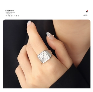 Detail of silver textured square shield ring with hammered finish on model's hand
