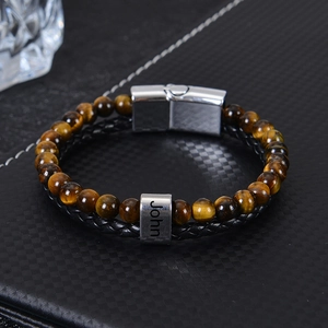 Close-up of men's leather stone bracelet with engraved name on polished stainless steel