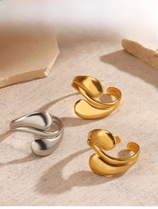 Detailed view of 18K gold and silver water drop rings on a minimalist stone display