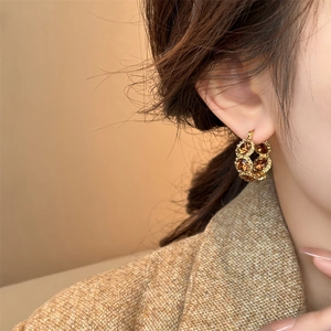 Close-up of model wearing 18k gold plated round earrings with amber stone detail