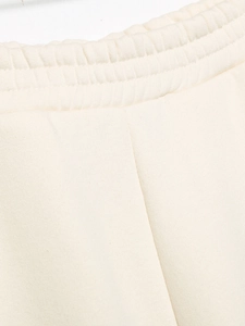 Détail de la taille élastiquée côtelée sur un jogging en maille crème avec coutures renforcées