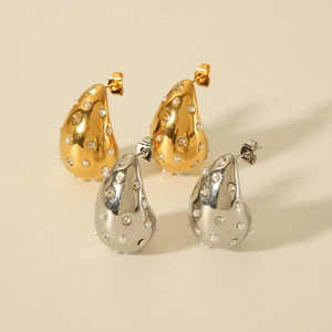 Detailed view of teardrop earrings with polished gold and silver finish, pearls and crystals