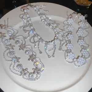 Detailed view of floral rhinestone and pearl necklaces on a white porcelain plate