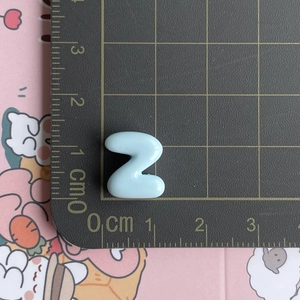 Close-up of light blue resin letter Z accessory on a cm scale cutting mat for DIY crafts