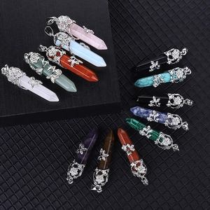Variety of hexagonal crystal point pendants with decorative silver tops on black background