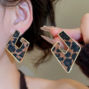 Detail of geometric rhombus earrings with golden metal frames and leopard print texture