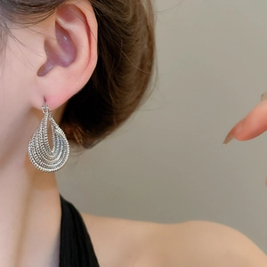 Close-up of textured silver layered teardrop earrings on a model showing metallic details
