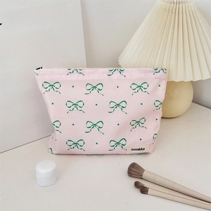 Close-up of pink floral toiletry bag with bow patterns and zipper on a marble desk