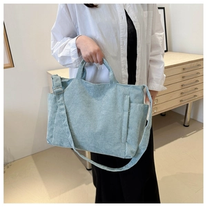 Detail of light blue corduroy tote bag showing side pocket and textured fabric surface