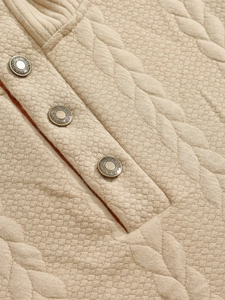 Macro view of beige jacquard knit fabric showing waffle texture and branded buttons