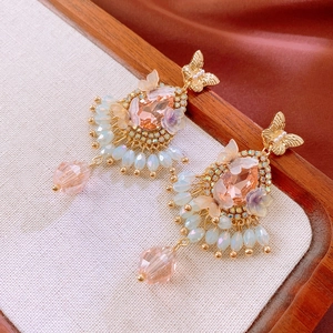 Detail of vintage bow earrings with champagne teardrop gems and white beaded tassels