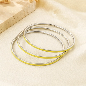 Detailed view of silver stackable bangles with vibrant yellow enamel finish and stone accents
