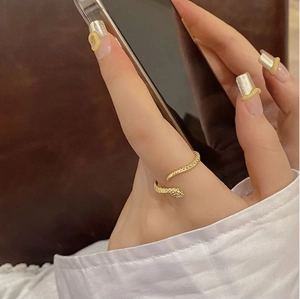 Detailed view of an adjustable gold snake ring with realistic scale textures on finger