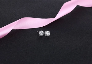 Macro detail of round S925 silver stud earrings with pave crystals and pink ribbon