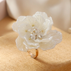 Detailed view of handcrafted white floral ring with layered petals and golden core