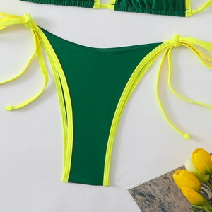 Detailed view of dark green bikini bottoms with bright yellow side ties and piping