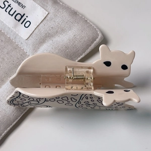 Detailed view of the cream cat-shaped acetate hair claw clip with black spotted pattern
