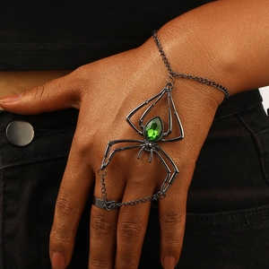 Detailed close-up of a gothic gun-black spider finger bracelet with a green gemstone
