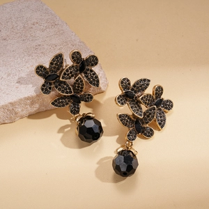 Gothic style gold floral earrings with black crystals and teardrop beads on stone