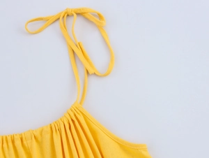 Detail of adjustable tie-up shoulder straps and gathered neckline on yellow summer dress