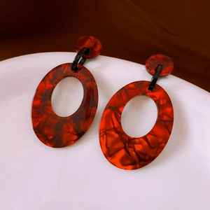 Detailed view of red-brown tortoiseshell acrylic oval earrings with polished texture