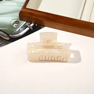 Detail of a pearlescent beige rectangle hair claw clip on a stylish aesthetic background
