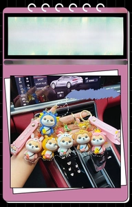 Close-up of cute zodiac Shiba Inu keychains with pink silicone hand straps in car interior