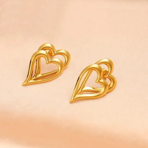 Nahaufnahme von hohlen 18K Gold Herz-Ohrsteckern auf elegantem rosa Seidenhintergrund