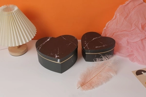 Detail view of heart-shaped gift boxes with black marble texture and gold accents