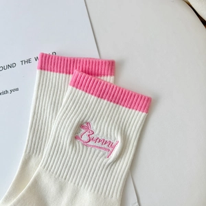 Close-up of pink Bunny embroidery and rib texture on white striped cotton socks