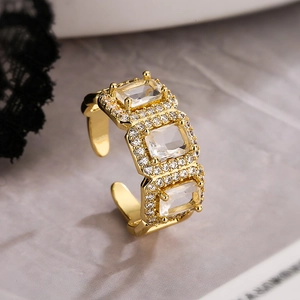 Adjustable gold plated open ring featuring three square gemstones and crystal accents