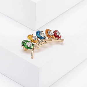 Detail of five colorful enamel birds with rhinestones on a golden metal branch brooch