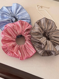 Gros plan de chouchous en tissu rayé rose, bleu et marron avec des perles élégantes