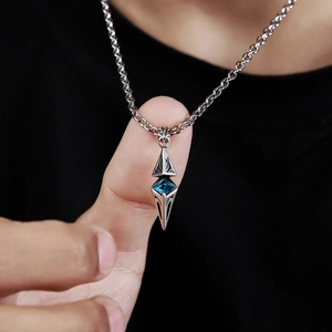 Macro detail of silver starburst pendant with blue gemstone and curb chain link