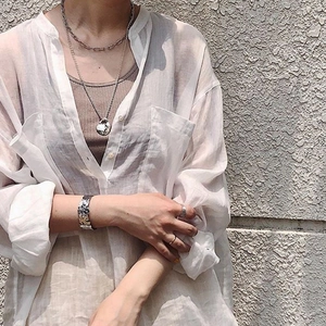 Gros plan du bracelet en métal texturé argenté et du collier superposé sur mannequin