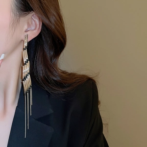 Close-up of elegant silver tassel earrings with black beads worn by a model in a suit