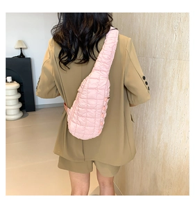 Détail d'un sac bandoulière matelassé rose avec sangle réglable porté sur un blazer kaki