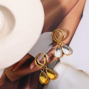 Detailed close-up of gold water drop earrings with clear and amber stones on ceramic tray