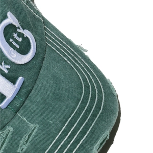 Close-up of distressed brim on dark green washed cotton baseball cap with NYC embroidery
