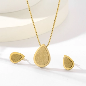 Detail view of gold teardrop jewelry set with matte finish and polished edges