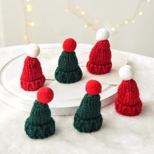 Red and green knitted Christmas mini hats with pom-poms for festive holiday decorations