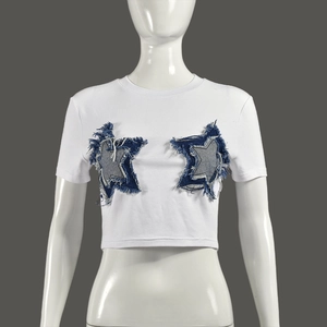 Close-up of white cropped T-shirt featuring denim star patches and frayed tassel details