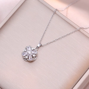 Détail du collier fleur rotatif en argent avec zircons sur une boîte en soie rose