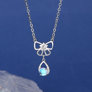 Silver bow necklace with shimmering moonstone drop pendant on a navy blue background