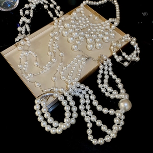 Detail view of elegant layered pearl necklaces and bracelets on a gold framed tray