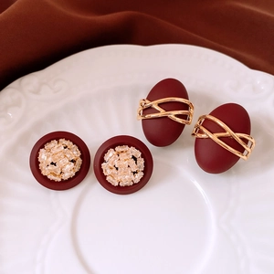 Détail de boucles d'oreilles rouge et or avec zircons sur une assiette en céramique